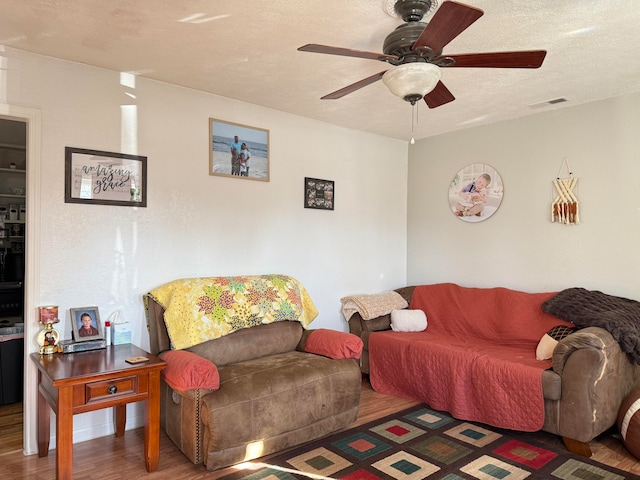 living room with a textured ceiling, dark hardwood / wood-style floors, and ceiling fan