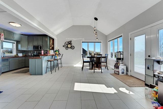 kitchen featuring wooden counters, decorative light fixtures, decorative backsplash, vaulted ceiling, and a kitchen breakfast bar