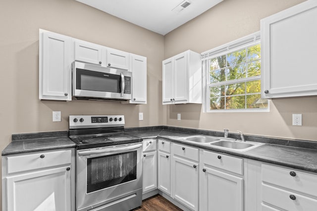 kitchen featuring stainless steel appliances, white cabinets, sink, and dark wood-type flooring