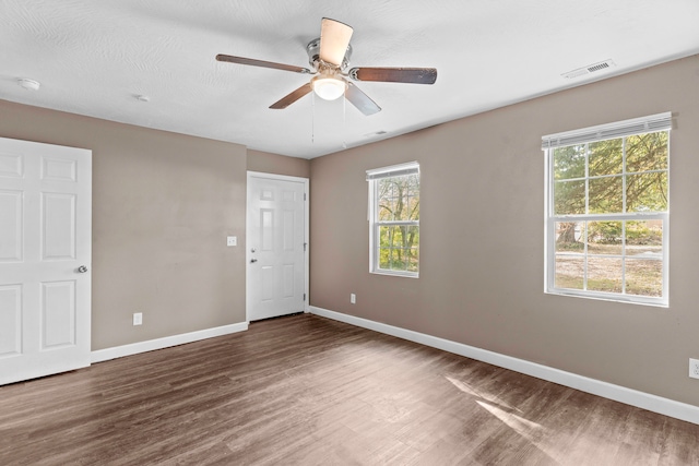 empty room featuring dark wood-type flooring, ceiling fan, and a textured ceiling