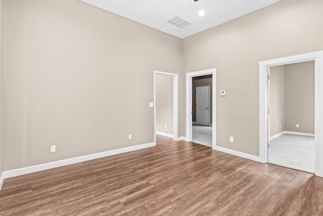 spare room featuring a towering ceiling and hardwood / wood-style floors