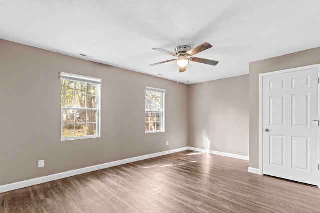 unfurnished room with a textured ceiling, a wealth of natural light, wood-type flooring, and ceiling fan