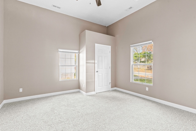 unfurnished room with light colored carpet and ceiling fan