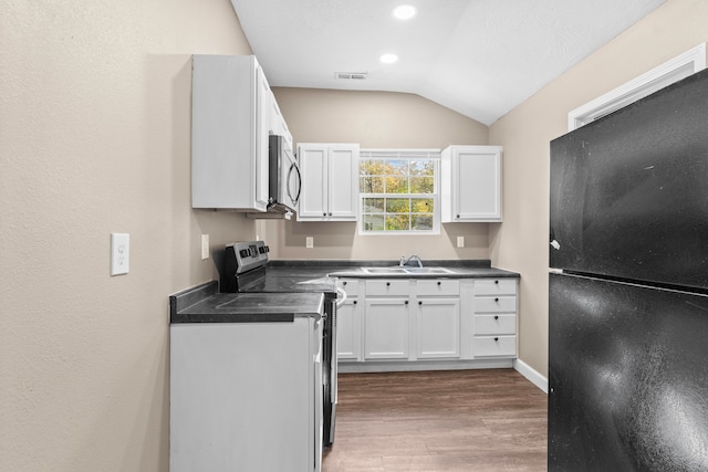 kitchen featuring stainless steel appliances, hardwood / wood-style flooring, sink, white cabinets, and vaulted ceiling