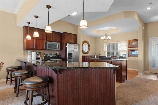 kitchen featuring ornamental molding, stainless steel appliances, hanging light fixtures, a kitchen breakfast bar, and kitchen peninsula