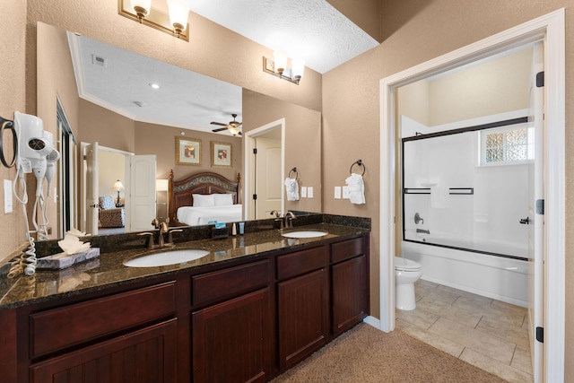 full bathroom featuring toilet, a textured ceiling, shower / bath combination with glass door, ceiling fan, and vanity