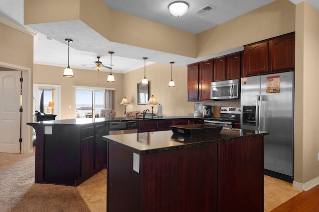 kitchen with kitchen peninsula, ornamental molding, a kitchen island, appliances with stainless steel finishes, and decorative light fixtures