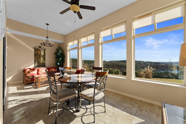 sunroom / solarium featuring a water view and ceiling fan with notable chandelier