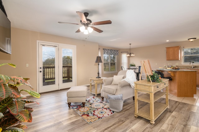 living room with sink, ceiling fan with notable chandelier, and light hardwood / wood-style flooring