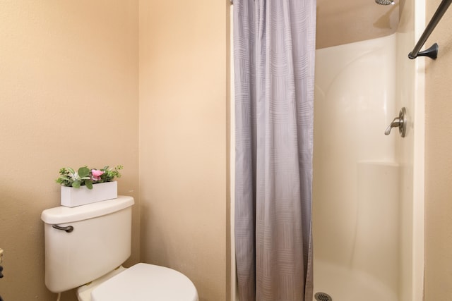 bathroom featuring toilet and curtained shower