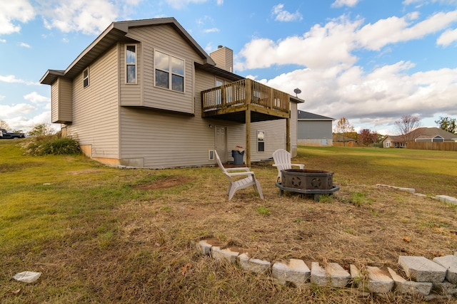 rear view of house featuring a lawn, a fire pit, and a wooden deck