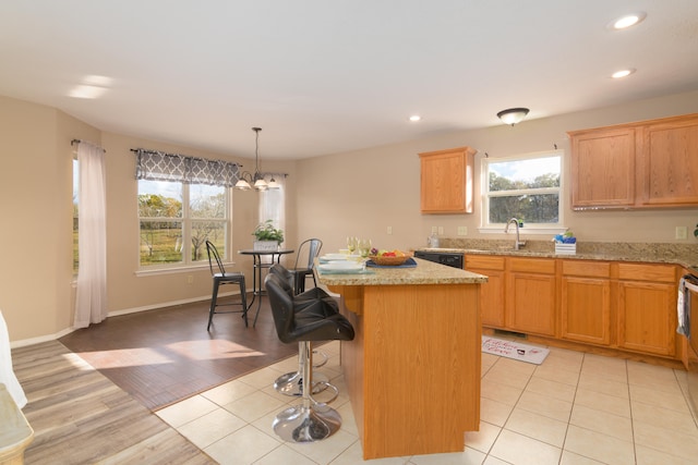 kitchen with a kitchen island, light wood-type flooring, decorative light fixtures, and a healthy amount of sunlight