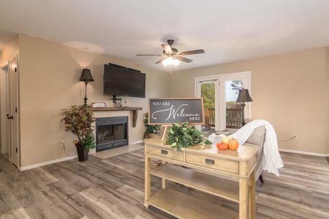 living room with hardwood / wood-style floors, a tiled fireplace, and ceiling fan