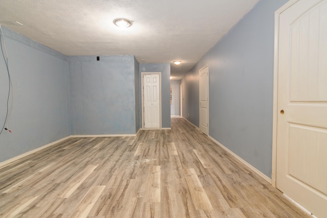 spare room with light wood-type flooring and a textured ceiling