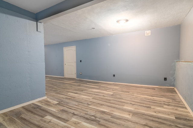 unfurnished room with light hardwood / wood-style floors and beam ceiling