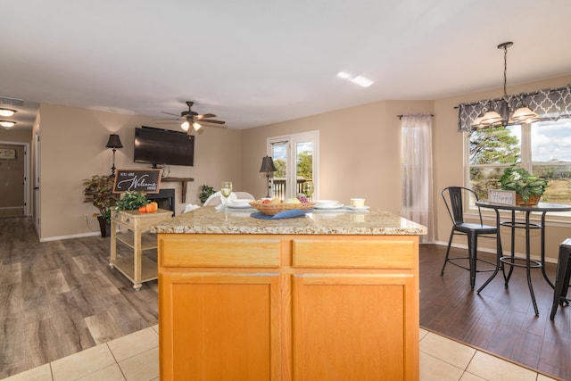 kitchen featuring a kitchen island, hanging light fixtures, ceiling fan with notable chandelier, and light hardwood / wood-style flooring