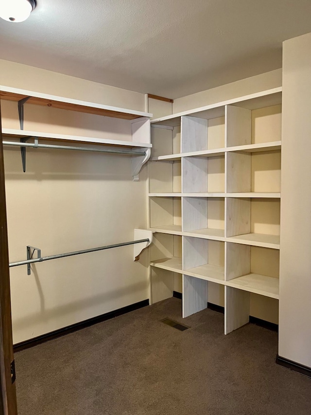 spacious closet featuring dark carpet