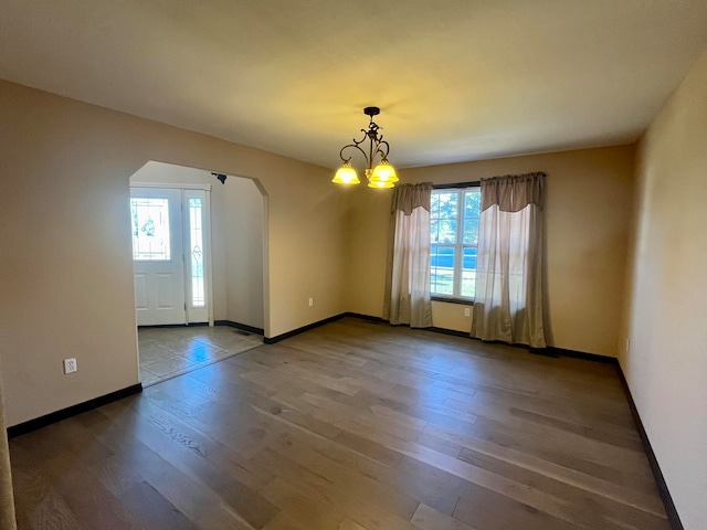 spare room with a notable chandelier and hardwood / wood-style flooring