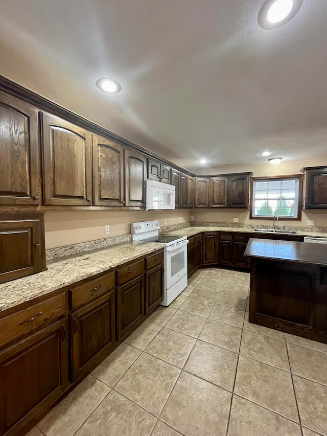 kitchen featuring dark brown cabinetry, light stone countertops, sink, white appliances, and light tile patterned floors