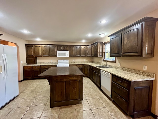 kitchen featuring dark brown cabinets, white appliances, sink, a center island, and light tile patterned flooring