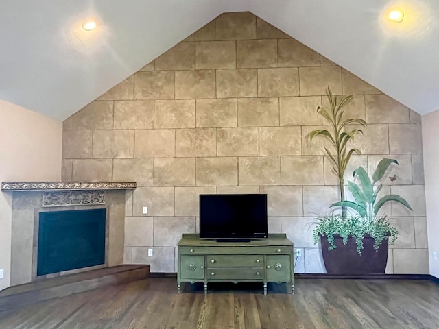 unfurnished living room featuring tile walls, vaulted ceiling, and hardwood / wood-style flooring