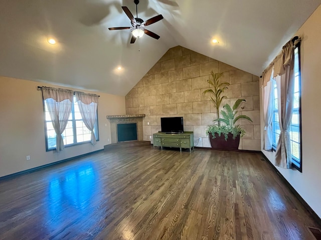 unfurnished living room with ceiling fan, wood-type flooring, tile walls, and vaulted ceiling