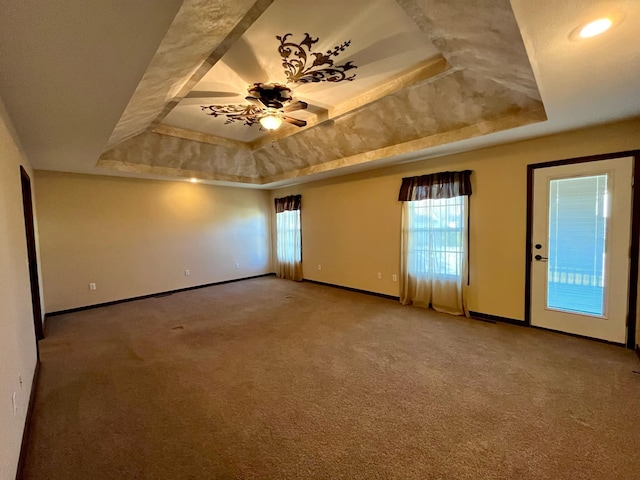 spare room with carpet floors, a raised ceiling, and ceiling fan