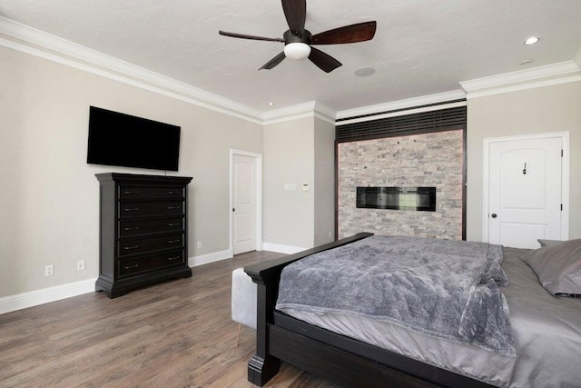 bedroom with a fireplace, hardwood / wood-style flooring, ceiling fan, and ornamental molding