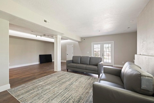 living room featuring dark wood-type flooring, a textured ceiling, and french doors