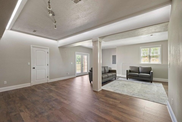 living room with track lighting, dark hardwood / wood-style floors, a textured ceiling, ornate columns, and french doors