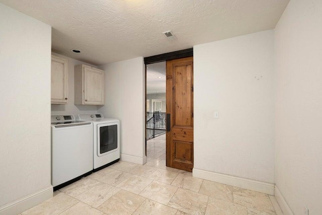 laundry area with a textured ceiling, cabinets, and washer and dryer