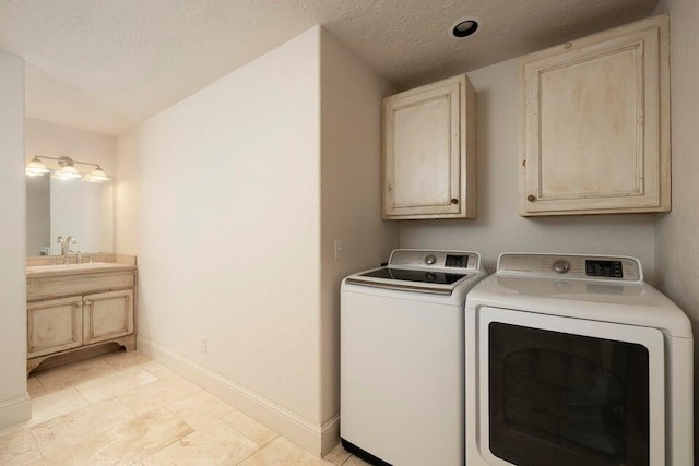 clothes washing area featuring cabinets, sink, a textured ceiling, light tile patterned floors, and washer and dryer