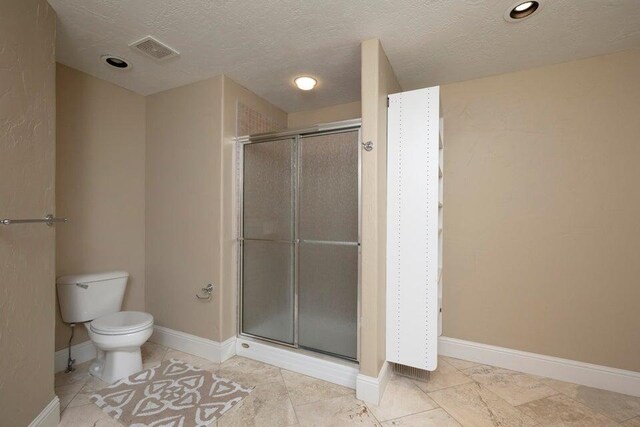 bathroom featuring walk in shower, toilet, and a textured ceiling