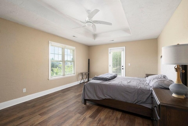 bedroom featuring dark hardwood / wood-style flooring, ceiling fan, and a raised ceiling