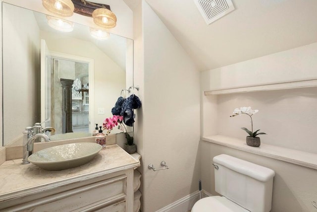 bathroom featuring vanity, toilet, and vaulted ceiling