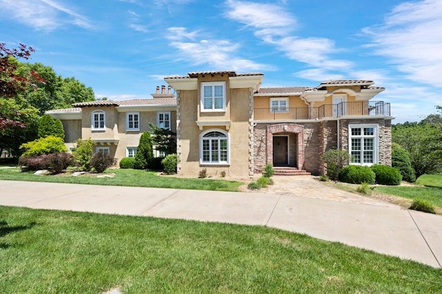 mediterranean / spanish-style house featuring a front lawn and a balcony