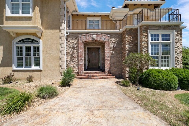 view of exterior entry with a balcony