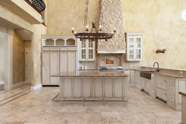 kitchen featuring a kitchen bar, light stone countertops, pendant lighting, sink, and a center island