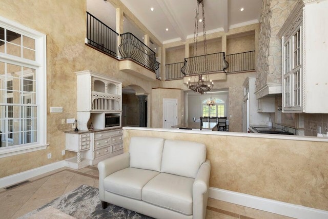 kitchen featuring hanging light fixtures, a towering ceiling, a chandelier, and white cabinetry