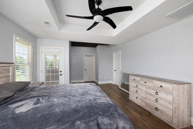 bedroom featuring ceiling fan, a textured ceiling, a raised ceiling, dark hardwood / wood-style flooring, and access to outside