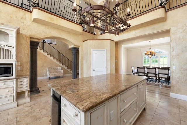 kitchen featuring a high ceiling, decorative columns, and a chandelier