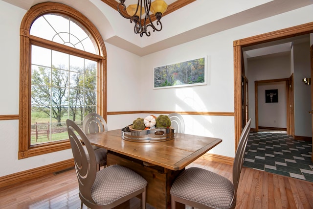 dining area featuring light wood-type flooring, a wealth of natural light, and a notable chandelier