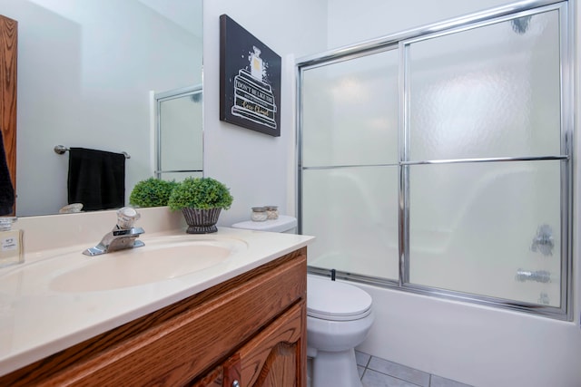 full bathroom with vanity, tile patterned floors, combined bath / shower with glass door, and toilet