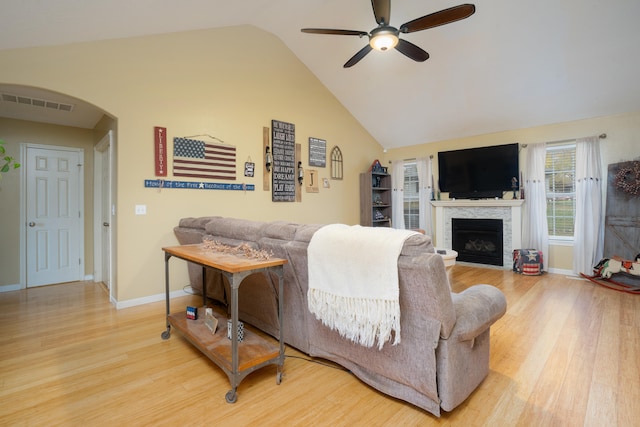 living room with wood-type flooring, vaulted ceiling, ceiling fan, and a fireplace