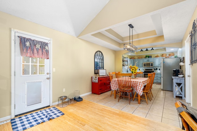 dining room featuring light wood-type flooring, a notable chandelier, and a raised ceiling