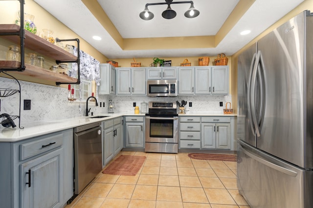 kitchen featuring gray cabinetry, sink, a raised ceiling, and stainless steel appliances