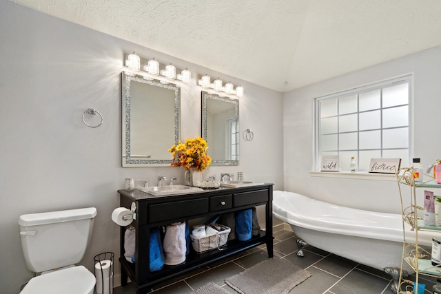 bathroom with tile patterned flooring, a textured ceiling, vanity, a bath, and toilet