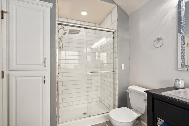 bathroom with toilet, vanity, a textured ceiling, and a shower with door