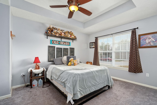 carpeted bedroom with ceiling fan and a raised ceiling