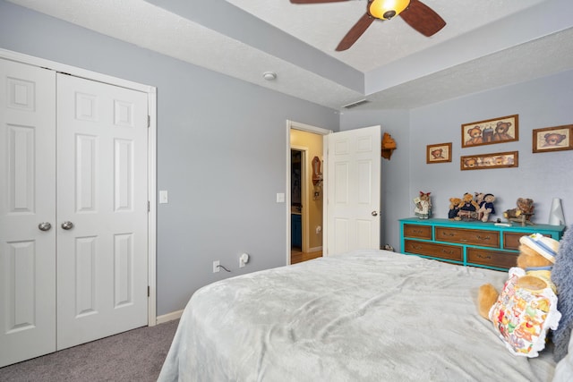 carpeted bedroom with ceiling fan, a textured ceiling, and a closet